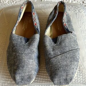 Toms denim look slip ons with navy blue and orange Aztec trim. Size 7